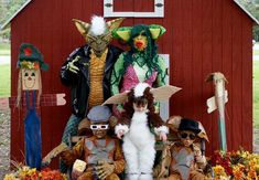 a group of people dressed in costumes sitting on top of a chair next to a red barn