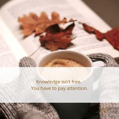 a cup of coffee sitting on top of an open book