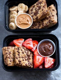 two plastic trays filled with different types of food next to bananas and strawberries