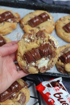 a hand holding a chocolate chip cookie with marshmallows in the middle and one bite taken out