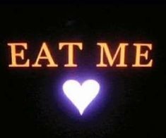 the words eat me are lit up at night with a heart shaped light in the middle