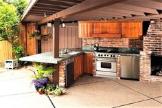 an outdoor kitchen with grill, sink and oven