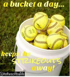 a bucket full of yellow softballs sitting on top of a green grass covered field