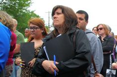 a group of people standing next to each other holding notebooks and pens in their hands