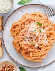 a plate of pasta with sauce and parmesan cheese on top, next to garlic bread