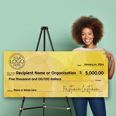 a woman holding up a large yellow check for $ 5, 000 in front of a green background