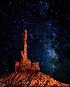 the night sky is filled with stars and bright lights, as well as an image of a tall rock formation