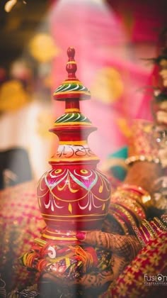 an ornately decorated vase sitting on top of a cloth covered table with other decorations