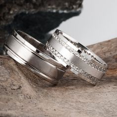 two wedding rings sitting on top of a piece of wood next to another ring with diamonds