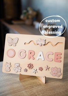 a wooden sign that says grace with flowers and butterflies on it, sitting on a table