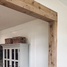 an empty room with white walls and wooden beams on the wall, including a cabinet