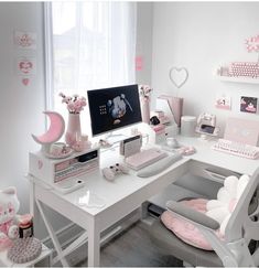 a white desk topped with a computer monitor and keyboard next to a pink moon shaped pillow