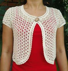 a woman wearing a red shirt and white crochet cardigan with a button on the front