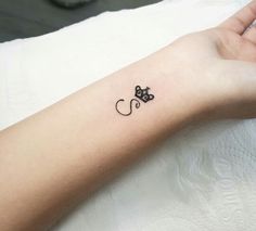 a small black cat tattoo on the wrist