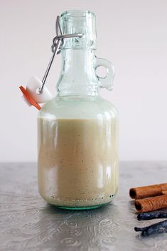 a glass bottle filled with liquid next to cinnamon sticks