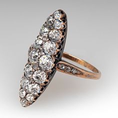 This lovely circa mid-to-late Victorian era silver topped 14k yellow gold ring. The navette shaped gallery is accented with sixteen (16), semi-bezel/bead set, old European cut diamonds and six (6), bead set, rose cut diamonds. The shoulders of the ring are each accented with three (3), bead set, rose cut diamonds. The ring measures 26.2mm at the top, rises 5.5mm above the finger, tapering to 1.4mm wide and 0.8mm thick at the base of the shank. It is currently a size 7. A few of the accent diamonds are chipped but this is not visible without magnification. Victorian Jewelry With 17 Jewels In Marquise Cut, Antique Marquise Diamond Ring With Prong Setting, Victorian Cluster Ring With Diamond Accents, Oval Shape, Victorian Oval Cluster Ring With Diamond Accents, Antique Oval Cluster Ring With Diamond Accents, Victorian Marquise Diamond Ring For Formal Occasions, Vintage Marquise Cluster Ring With Diamond Accents, Antique Marquise Diamond Cut Jewelry, Antique Marquise Jewelry With Single Cut Diamonds