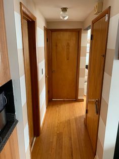 an empty hallway with wooden doors and hard wood flooring on either side of the door