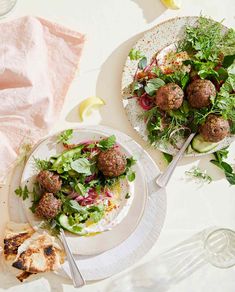 two plates with meatballs and salad on them