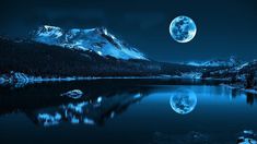 the full moon is shining over a mountain lake