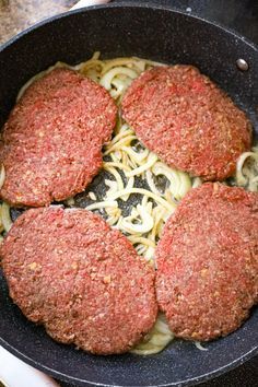 four hamburger patties are cooking in a skillet