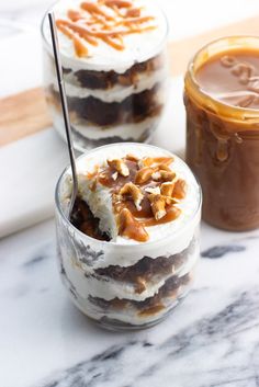 two desserts are sitting on a marble table with chocolate and caramel in the background