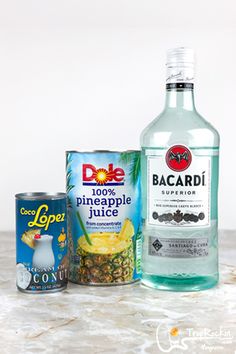 the ingredients to make pineapple punch are displayed on a marble countertop, including an empty can and a bottle of alcohol