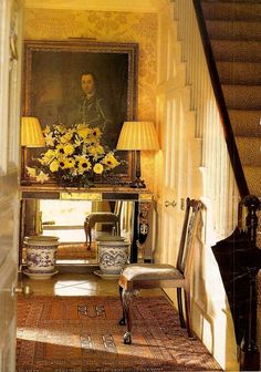 a painting is hanging on the wall next to a stair case with flowers in it