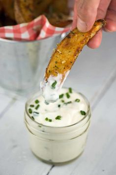 a person dipping some kind of food into a small glass jar with sour cream on it