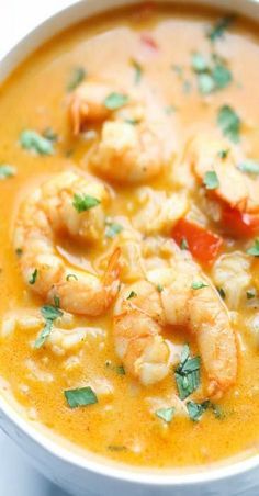 a white bowl filled with soup and shrimp on top of it's side,