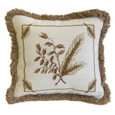 an embroidered pillow with fringes and leaves on it