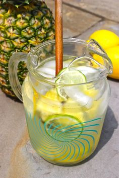 a glass pitcher filled with lemonade next to a pineapple on the side walk