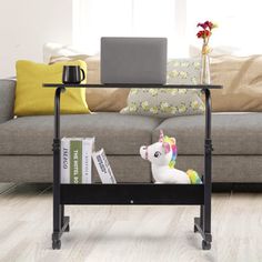 a laptop computer sitting on top of a glass table next to a couch with books