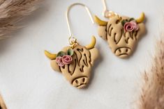 the earrings are decorated with flowers and bulls head heads on them, sitting on a piece of paper