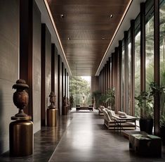 a long hallway with chairs and vases on the floor next to large glass windows