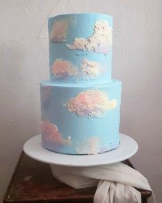 a three tiered cake with clouds painted on it