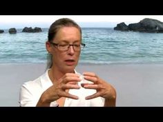 a woman standing on top of a beach next to the ocean holding a white frisbee