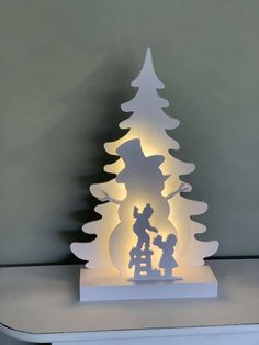 an illuminated christmas tree with snowman and children on it, sitting on top of a table