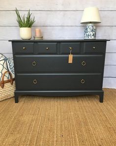 a black dresser sitting on top of a rug next to a lamp