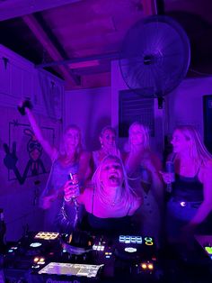 a group of women standing next to each other in front of a dj's mixer