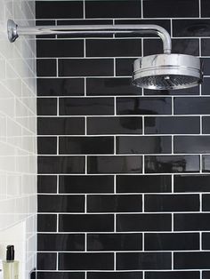 a shower head with black tiles on the wall