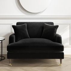 a living room with a black couch and round mirror on the wall next to it