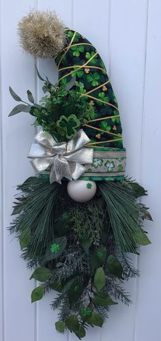 a christmas wreath with a green hat and greenery hanging on the front door ornament