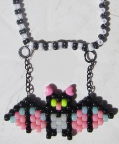 a necklace made out of plastic beads on a white surface with a black bead chain