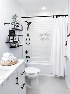 a white bathroom with black and white decor on the shower curtain, toilet, and bathtub