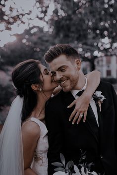 a bride and groom kissing in front of trees