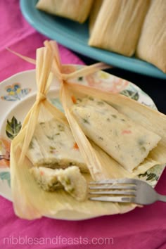 a plate with some food on it and a fork next to it, sitting on a pink table cloth