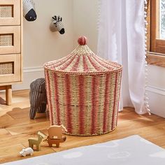 a large basket sitting on top of a hard wood floor next to a toy elephant