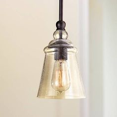 a light that is hanging from a ceiling fixture with a glass shade on the top