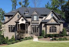 a large brick house with lots of windows and bushes in front of the house is surrounded by greenery