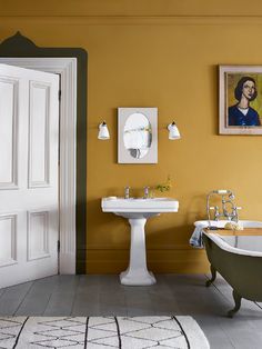 a bathroom with yellow walls and a claw foot bathtub in the center, an old fashioned sink on the far wall